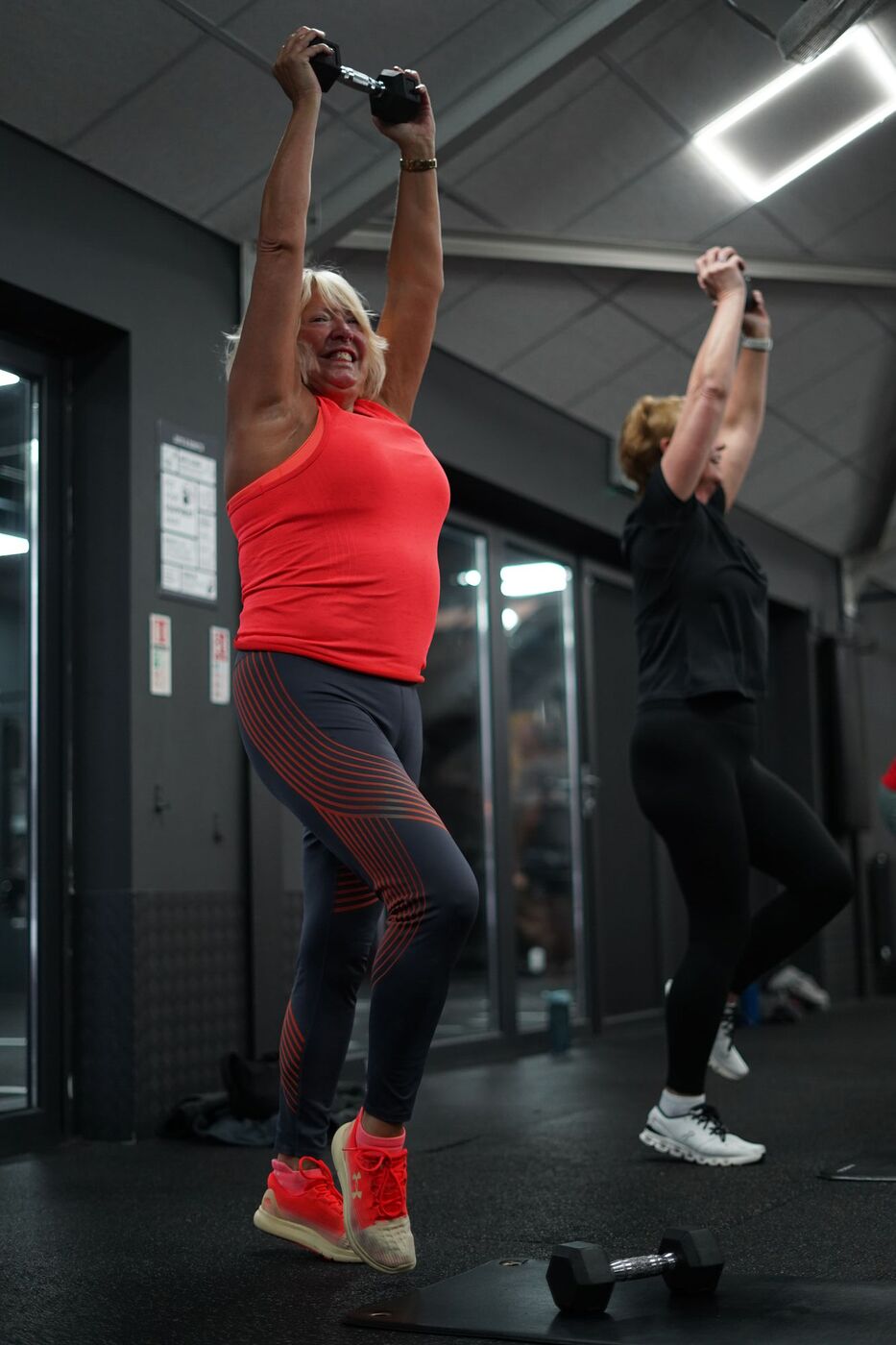 Members pressing dumbbells overhead in Sweat & Sculpt