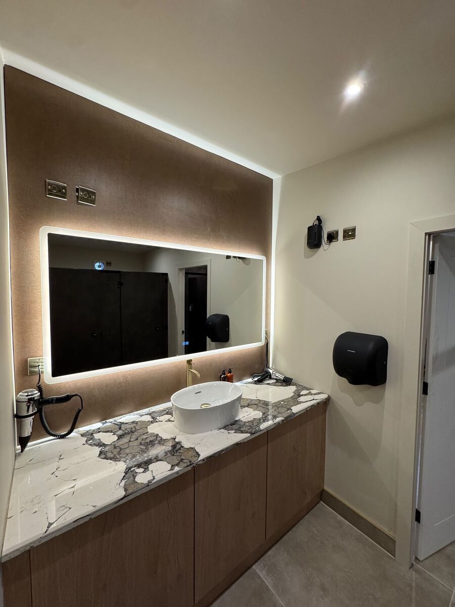Vanity area with lit mirror and hairdryer