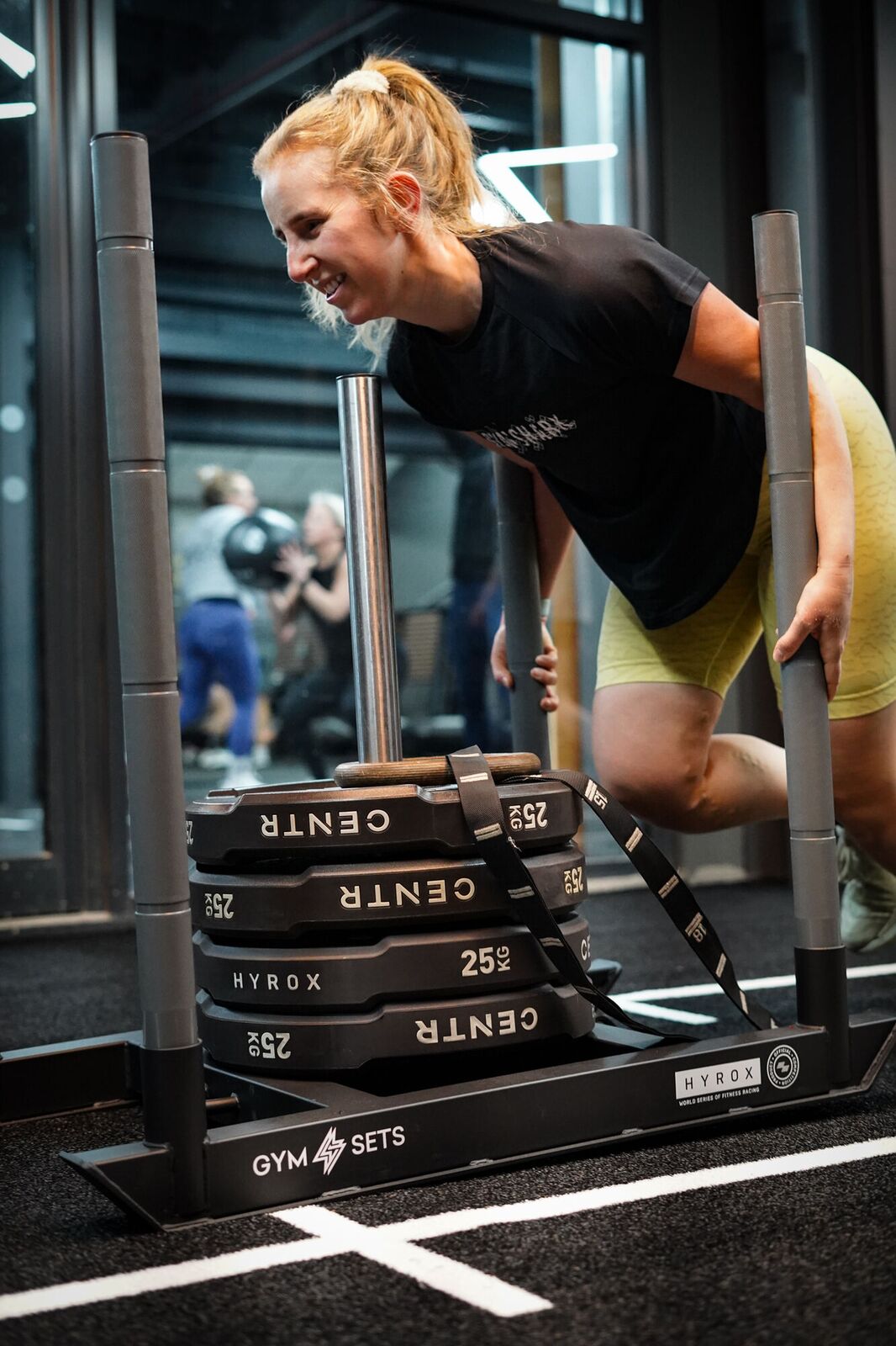 Member pushing a weighted sled on the HYROX track